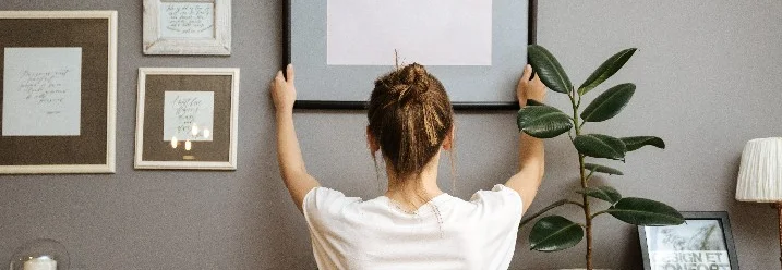 Person bringt Bilderrahmen an